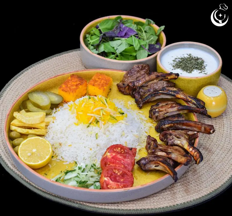 کباب شیشلیک بره اعلا با چلو زعفرانی و مخلفات شامل ماست، سالاد، گوجه، سیب‌زمینی و ترشی از رستوران کترینگ آسمان.