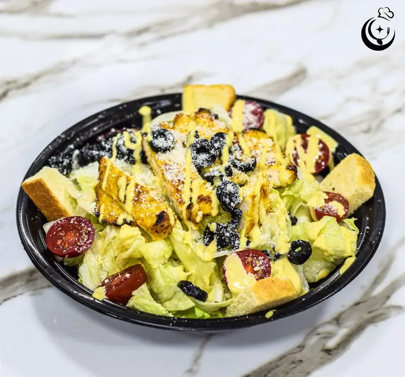 سالاد سزار مرغ گریل تازه و خوشمزه رستوران کترینگ آسمان، انتخابی سالم برای ناهار و شام. حاوی کاهو، زیتون، گوجه و سس مخصوص.