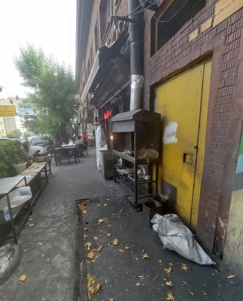 رستوران جیگر بلا: نمای بیرونی با فضای باز و منقل کباب‌پزی. مشتریان در حال لذت بردن از جیگر و کباب در محیط شلوغ.