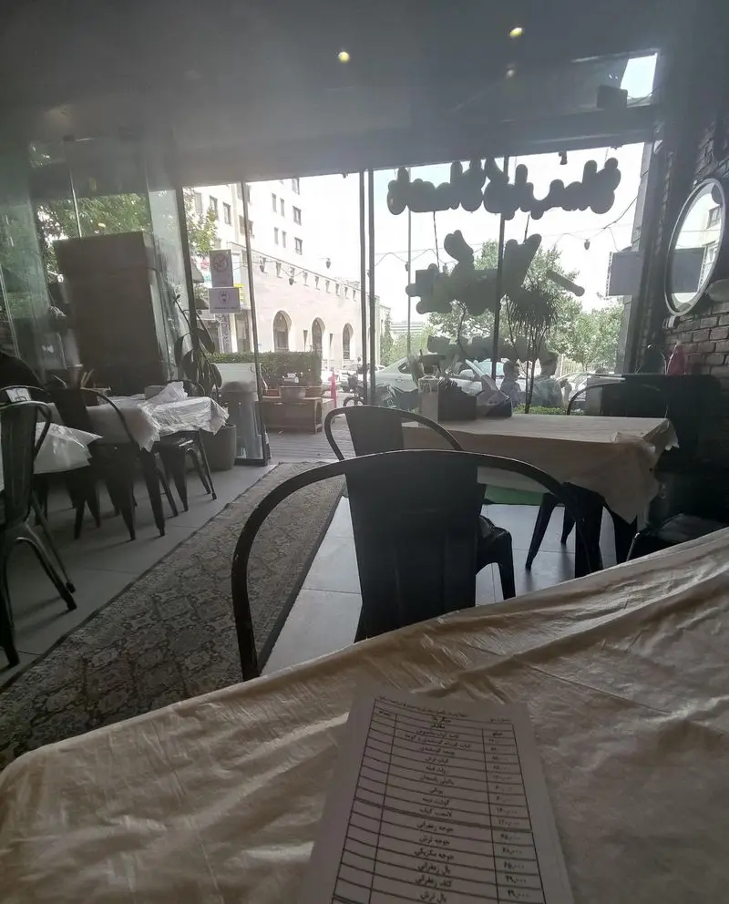 فضای داخلی دنج و دلنشین رستوران جیگر بلا با نمای زیبای شهری، میز و صندلی‌های شیک و منوی غذای خوشمزه