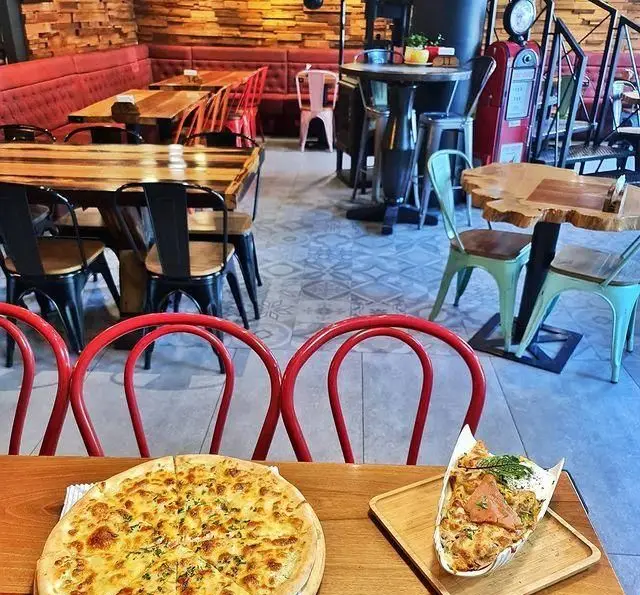 محیط دنج و زیبای کافه وصال، با طراحی داخلی جذاب، میزهای چوبی و مبلمان قرمز، همراه با پیتزاهای تازه و اشتهای برانگیز.