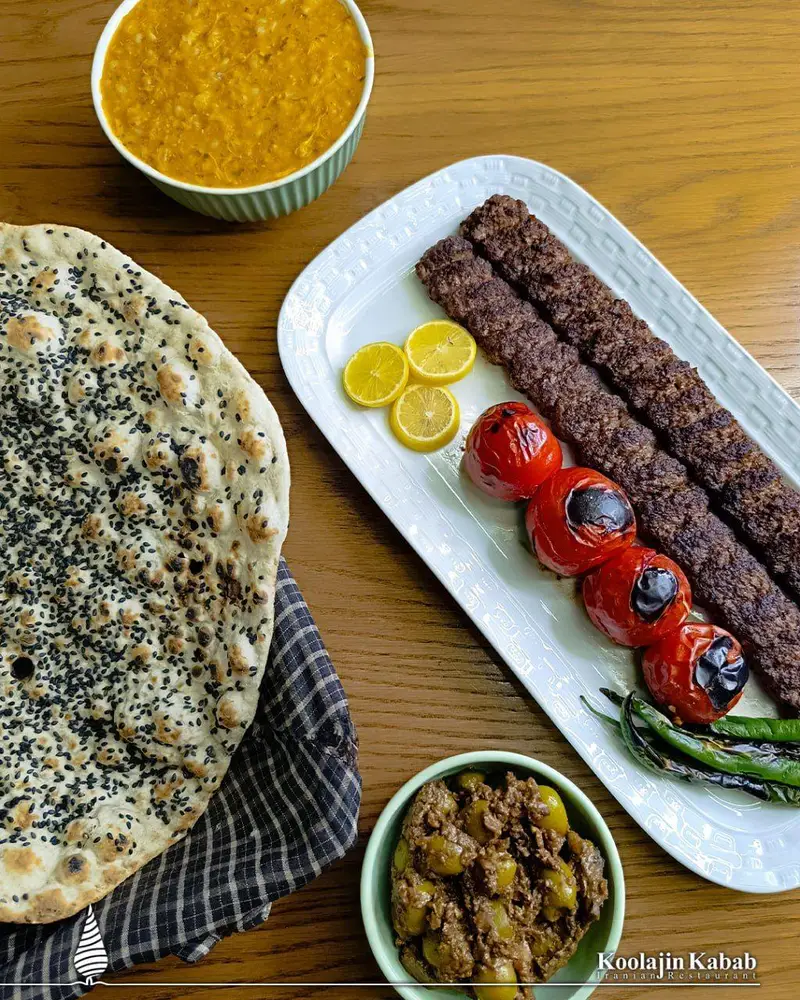 سفره ای از کباب کوبیده، نان، گوجه و فلفل کبابی، آش و زیتون پرورده؛ غذای اصیل ایرانی از آش و حلیم کولاژین سعادت آباد.