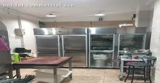 آشپزخانه صنعتی رستوران ایرانی پودات با تجهیزات کامل، شامل یخچال‌های استیل و میز کار، آماده برای تهیه غذاهای با کیفیت.