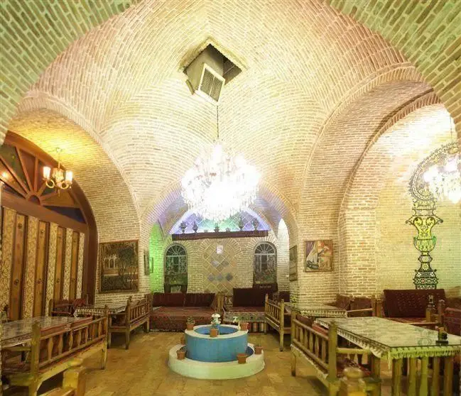 تصویری جذاب از فضای داخلی رستوران سنتی خیام با معماری سنتی، سقف‌های آجری زیبا، حوضچه فیروزه‌ای و مبلمان چوبی کلاسیک.