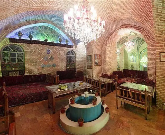 نمای داخلی رستوران سنتی خیام با معماری اصیل ایرانی، طاق‌های آجری، لوستر زیبا، تخت‌های سنتی و حوض دلنشین، فضایی گرم و دعوت‌کننده.