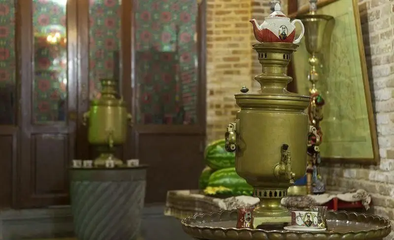 دو سماور برنجی باشکوه با قوری و استکان چای در محیط دلنشین رستوران سنتی خیام، جلوه‌ای از پذیرایی گرم ایرانی و نوشیدنی‌های سنتی