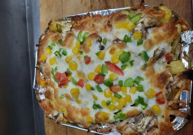 غذای پنیری و خوشمزه از پیتزا ساندویچ آیدا با پنیر آب شده، ذرت، فلفل دلمه و گوجه. مناسب برای سفارش و لذت بردن.