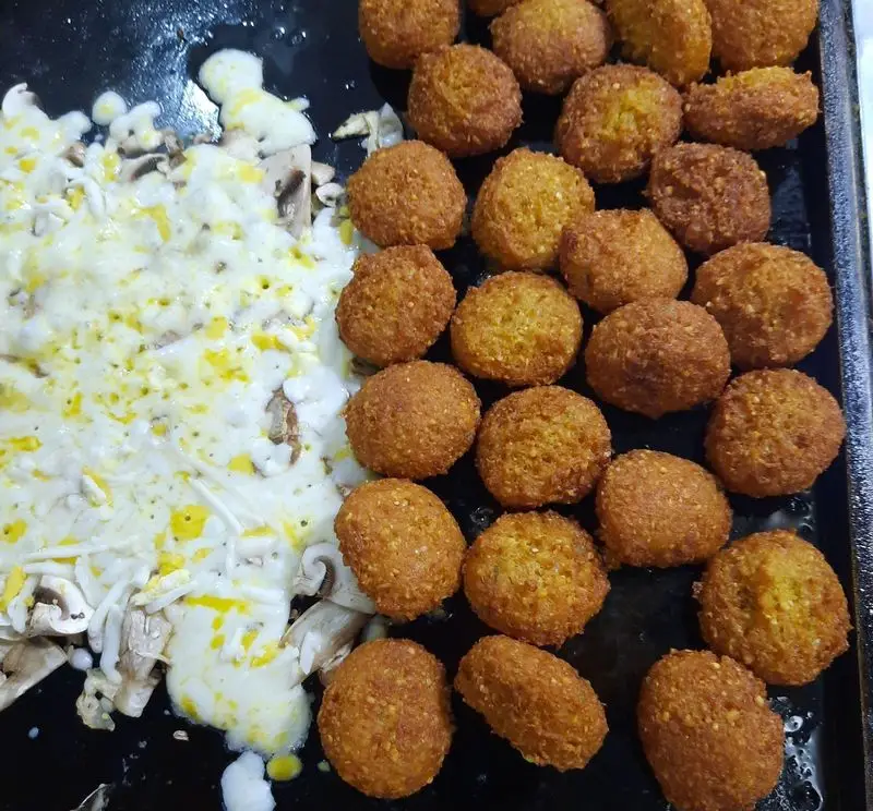 فلافل‌های ترد و طلایی در کنار قارچ‌های تازه و پنیر آب شده، آماده سرو از پیتزا ساندویچ آیدا. غذایی لذیذ برای ساندویچ و پیتزا.