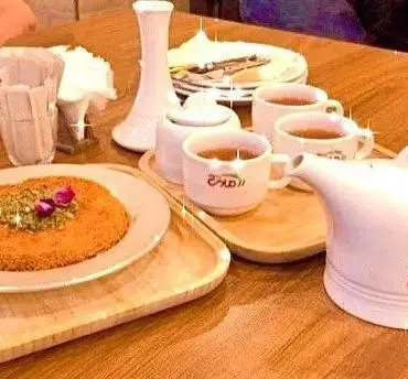 میز دسر کونفه پسته و چای در رستوران رزماری، شامل ظروف شیک و سفید، مناسب برای عصرانه یا دورهمی دوستانه در کافه رزماری.