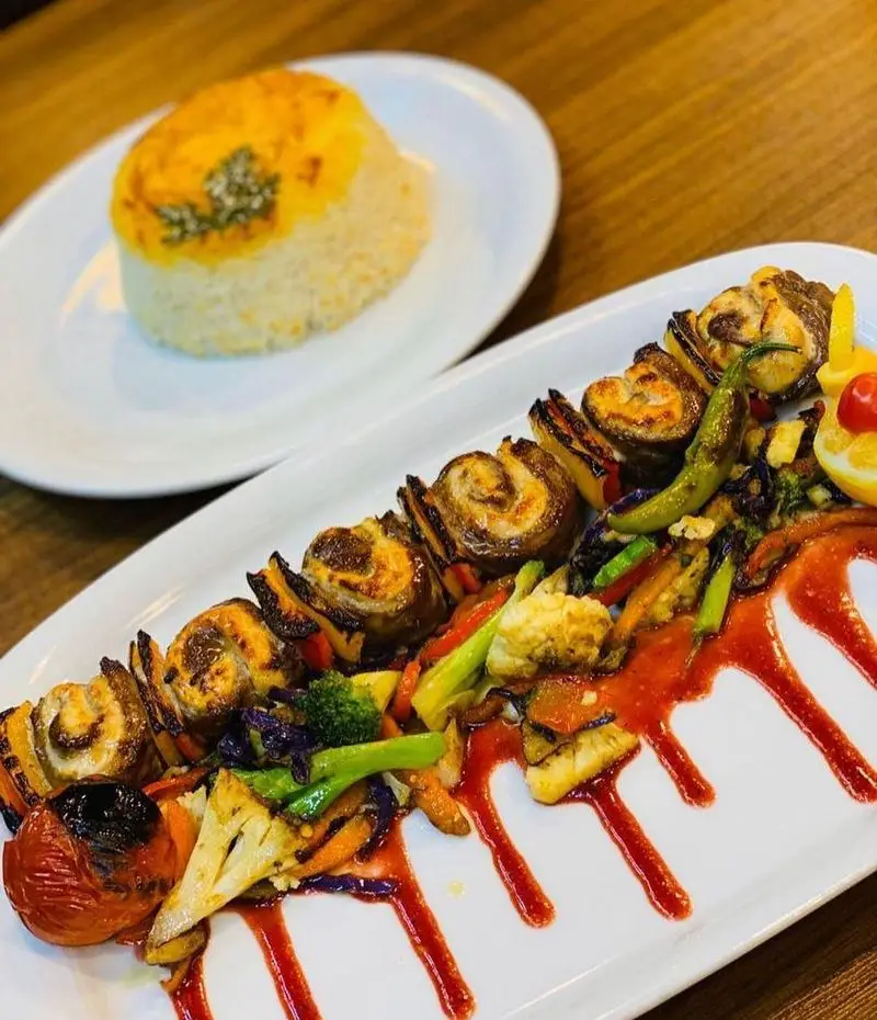 کباب رول گوشت لذیذ رستوران رزماری به همراه سبزیجات گریل متنوع، پلو زعفرانی معطر؛ انتخابی عالی برای یک غذای اصیل ایرانی.