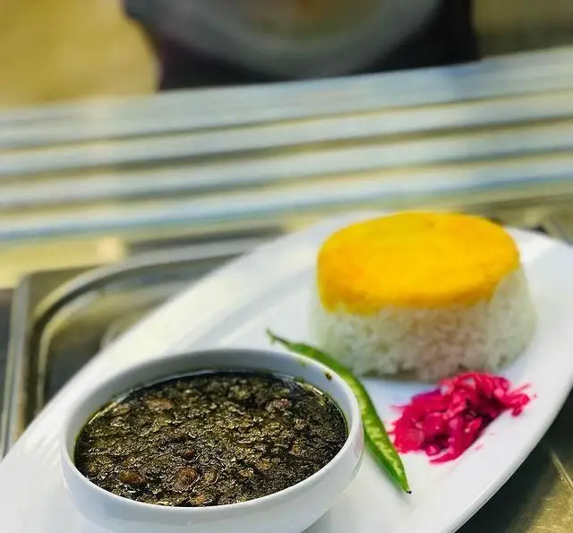 غذای کامل و خوشمزه ایرانی از رستوران رزماری: قورمه سبزی مجلسی با برنج زعفرانی، فلفل سبز تازه و ترشی خوشرنگ.