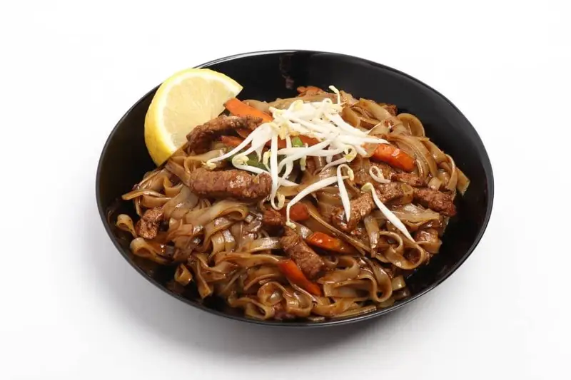 کاسه نودل پهن Pad See Ew با بیف لذیذ، هویج و جوانه ماش از رستوران آسیایی توکیو. یک غذای تایلندی تازه و خوش طعم.