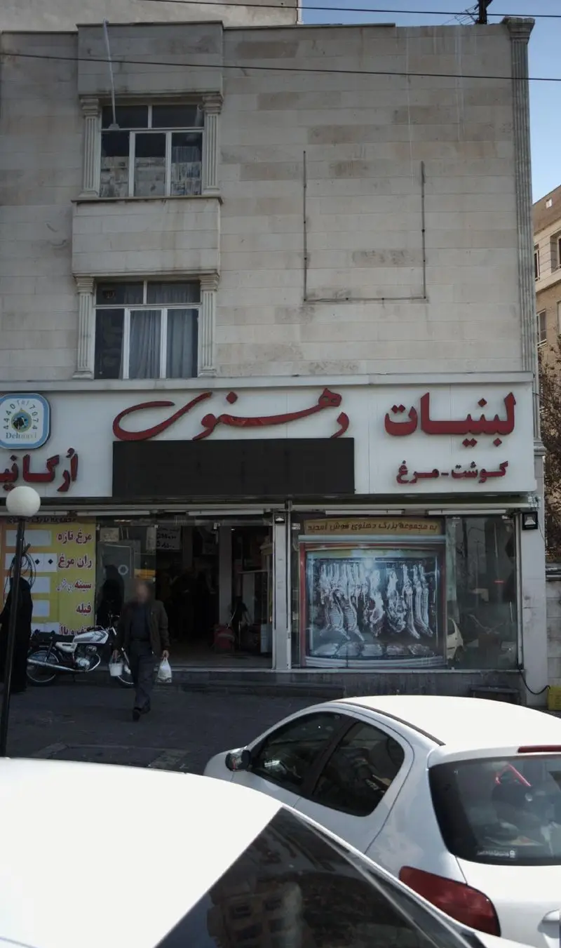 نمای بیرونی فروشگاه لبنیات ارگانیک دهنوی، عرضه کننده گوشت و مرغ تازه، با ویترین محصولات و معماری کلاسیک ساختمان.