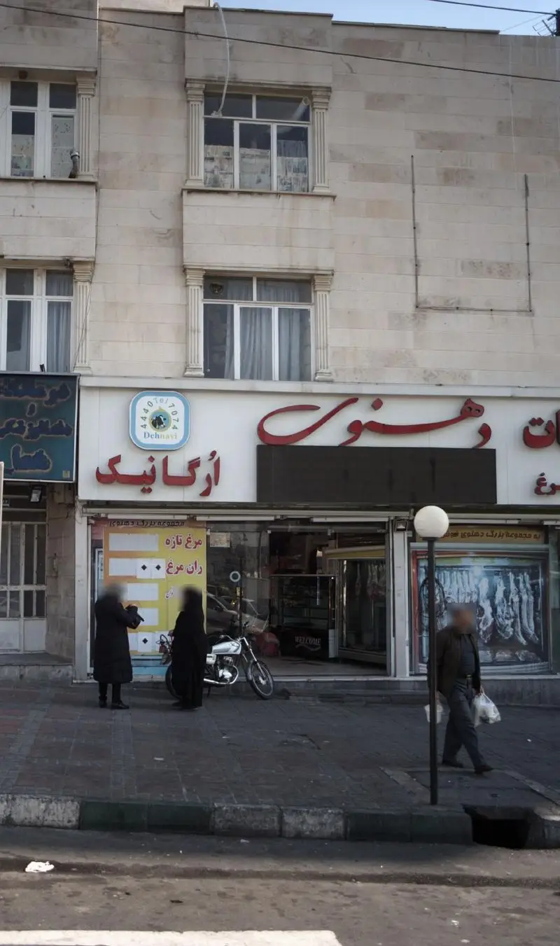نمای بیرونی فروشگاه لبنیات و مرغ ارگانیک دهنوی، با تابلوی روشن Dehnavi و مشتریان در حال خرید در پیاده‌رو.