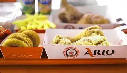 میز پر از غذاهای فست فود آریو: مرغ سوخاری طلایی و تازه، سیب زمینی سرخ کرده ترد و داغ به همراه مخلفات خوشمزه در ظروف یکبار مصرف.