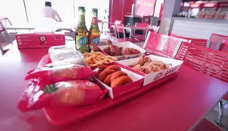 فست فود آریو: میز غذای پر از مرغ سوخاری، سیب زمینی سرخ کرده و ناگت در محیط گرم و دلنشین رستوران آریو برای مشتریان.