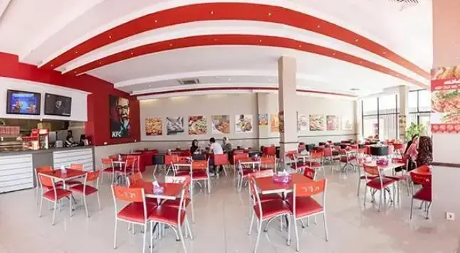 نمایی از فضای داخلی فست فود آریو، با طراحی مدرن و رنگ‌های قرمز و سفید، شامل میز و صندلی‌های شیک و محیطی مناسب برای مشتریان