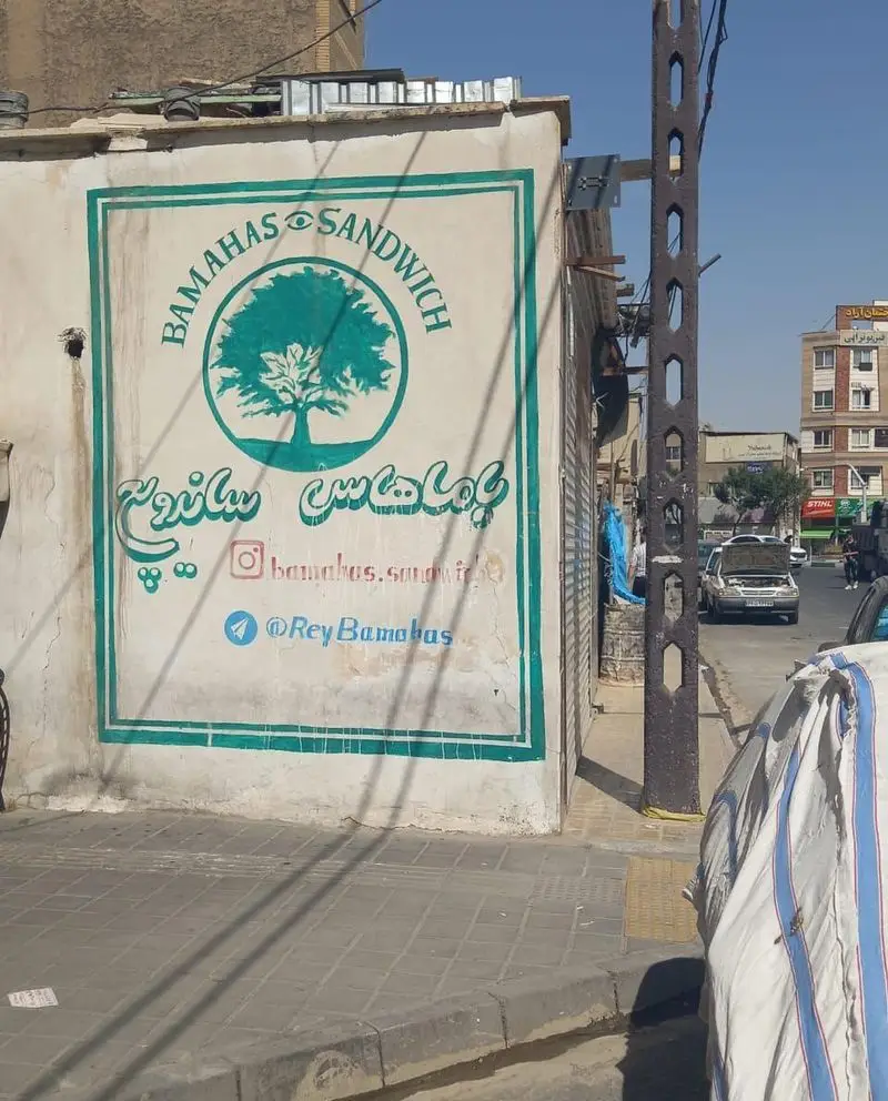 تابلوی فست فود باماهاس ساندویچ در شهرری با لوگوی درخت، نمایشگر آدرس اینستاگرام و تلگرام @ReyBamahas برای سفارش آسان و سریع.