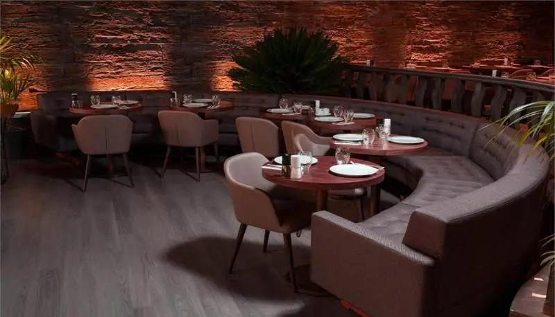 تصویری از دکوراسیون داخلی دلنشین و مدرن رستوران کاساب، شامل میز و صندلی‌های شیک، نیمکت منحنی و نورپردازی گرم محیط.