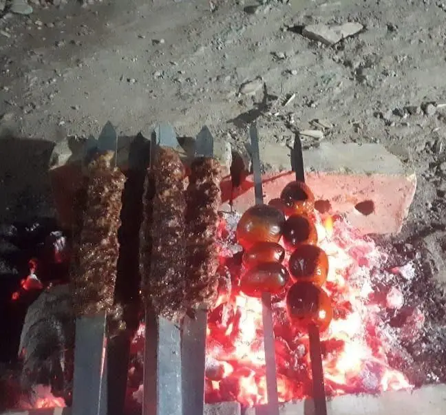 لذت تجربه طعم اصیل کباب و جگر تازه به همراه گوجه کبابی لذیذ روی زغال داغ در جگرسرای وحید، فضای باز شب.