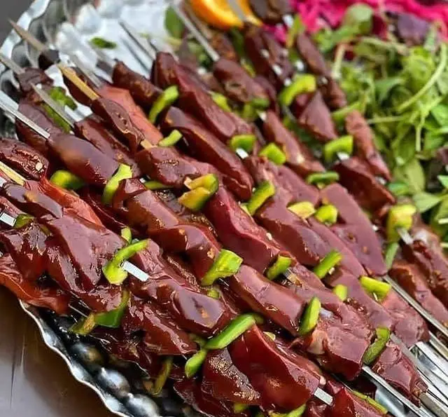 کباب جگر و دل گوسفندی تازه و لذیذ، سیخ شده با فلفل دلمه‌ای سبز، آماده سرو در سینی براق در جگرسرای وحید، با سبزیجات تازه.
