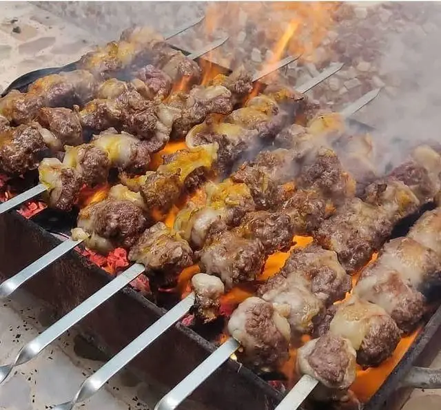 کباب های داغ و لذیذ جگر، دل و قلوه جگرسرای وحید در حال پخت بر روی منقل داغ با شعله های زغال. بوی کباب تازه در فضای باز.