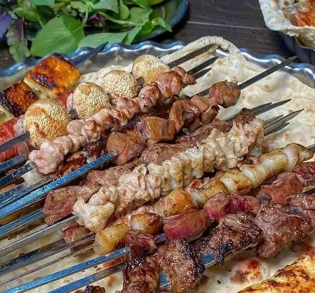 تصویری جذاب از انواع کباب جگر، دل، گوشت، قارچ و پنیر هالومی گریل شده، آماده سرو روی نان تازه در جگرسرای وحید.