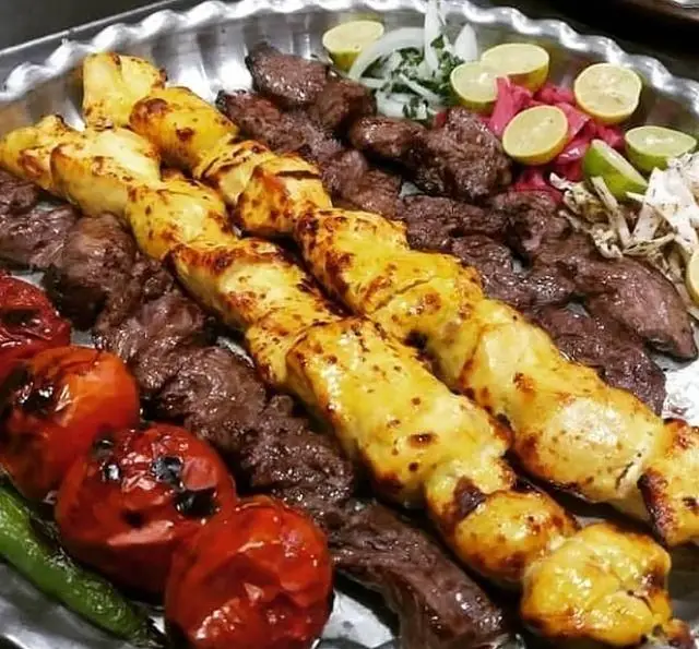 بشقاب اشتهابرانگیز کباب مخلوط جگرسرای وحید شامل دو سیخ جوجه کباب، کباب گوشت، گوجه کبابی، فلفل و مخلفات تازه.