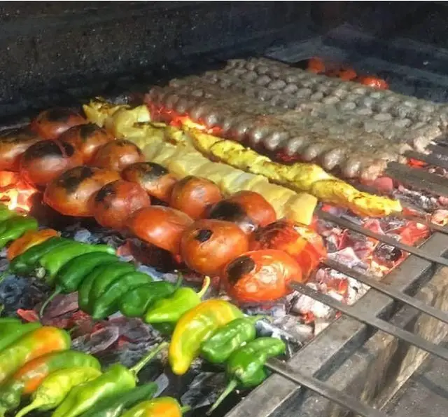 کباب کوبیده، جوجه کباب، گوجه کبابی و فلفل‌های سبز تازه که با حرارت زغال در حال پخت هستند، از جگرسرای وحید