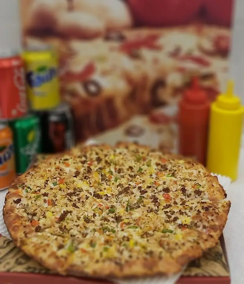 پیتزا با گوشت و سبزیجات تازه و رنگارنگ در فست فود زنجیره‌ای پیانو، به همراه مجموعه‌ای از نوشابه‌ها و سس‌های خوش‌طعم. غذای کامل.