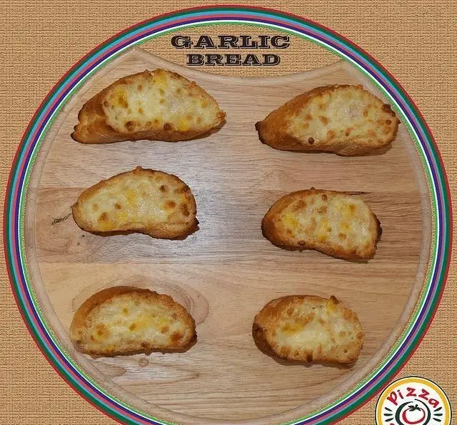 نان سیر پنیری خوشمزه فست فود پیانو: شش تکه نان سیر برشته با پنیر طلایی روی تخته چوبی، بهترین انتخاب برای شروع غذای ایتالیایی.