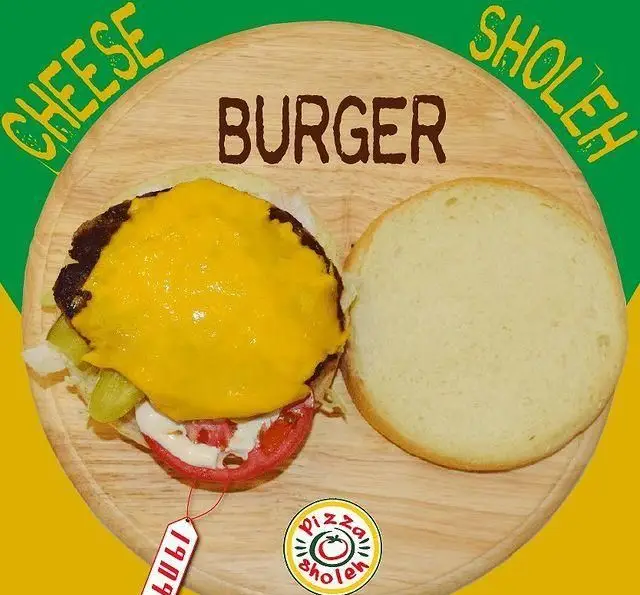 چیزبرگر شوله فست فود زنجیره‌ای پیانو: پتی گوشت، پنیر آب شده، گوجه، خیارشور و کاهو در نان باز روی تخته چوبی.