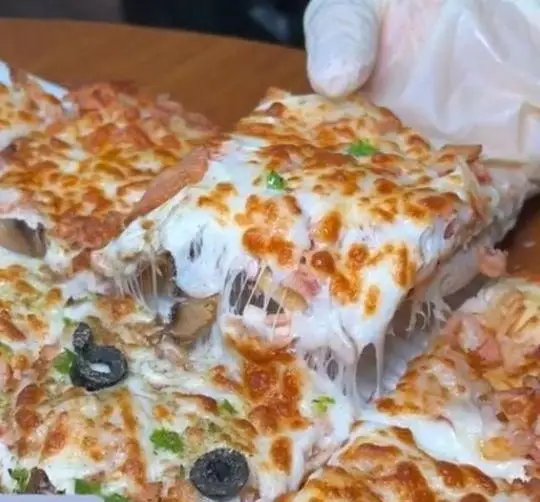 یک برش از پیتزای فوق‌العاده لذیذ فست فود زنجیره ای پیانو با پنیر موزارلای طلایی و کش‌دار، به همراه زیتون و قارچ تازه.