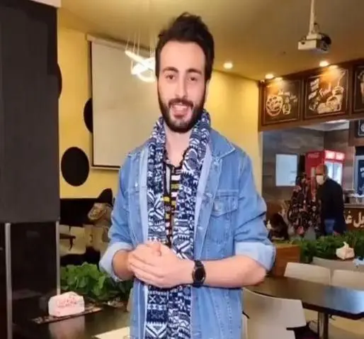 مردی جوان و خندان در محیطی دلنشین از فست فود زنجیره ای پیانو، آماده ارائه بهترین غذاهای سریع و تجربه مشتری عالی.