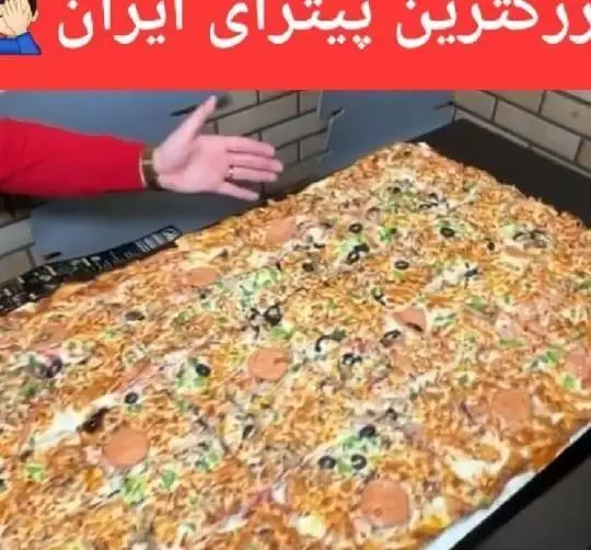 پیتزای بزرگ و مستطیلی با تاپینگ‌های متنوع مانند زیتون، سوسیس و پنیر، از فست فود زنجیره‌ای پیانو، بزرگترین پیتزای ایران.