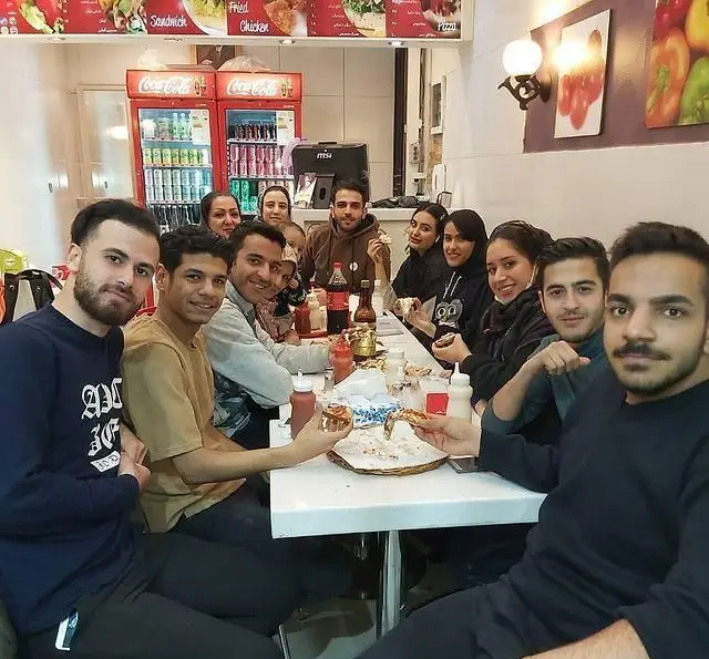 مشتریان شاد و راضی در فست فود زنجیره ای پیانو، مشغول لذت بردن از پیتزاهای متنوع در محیطی دلنشین.