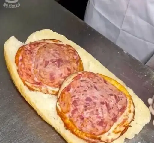 یک ساندویچ کالباس لذیذ و پرملات، با نان باگت تازه و تکه‌های بزرگ کالباس درجه یک در حال آماده‌سازی در فست فود پیانو.